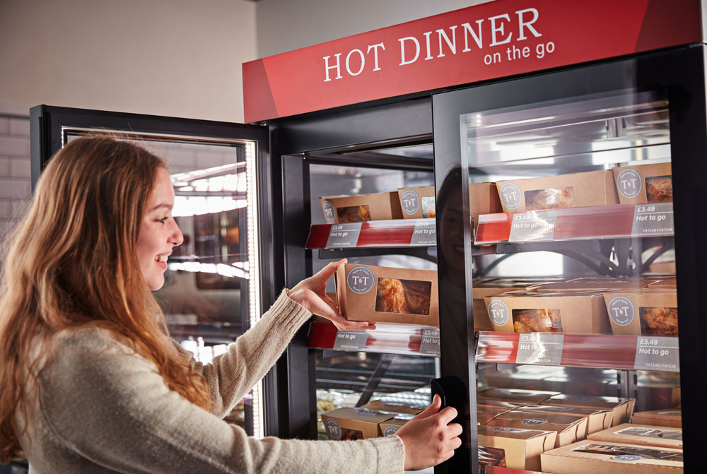 Girl taking rotisserie chicken box out of Flexeserve hot food-to-go unit in supermarket