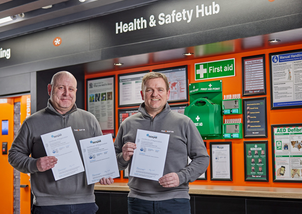 [L-R] Anthony Stubbs, HSEQ Manager and Mark Manley, Director of Manufacturing Operations standing by the Flexeserve Health & Safety Hub with ISO certifications 9001, 14001 and 45001